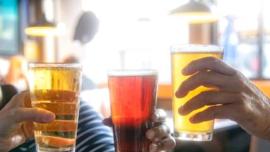 Three people clinking glasses of beer in a brewery taproom