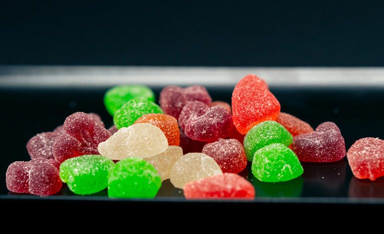 A close-up of colorful sugar-coated Delta-8 THC gummies in various shapes and colors