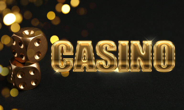 Golden casino dice stacked beside a bold, glowing gold “CASINO” text on a dark background with bokeh lights.