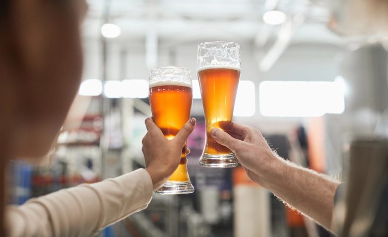 Two people holding craft beer glasses, celebrating money-savvy drinking habits.