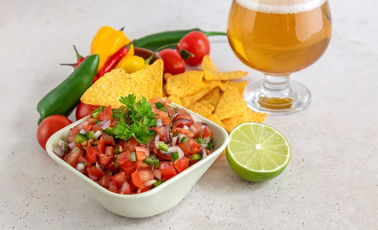 Fresh homemade salsa with tortilla chips, lime, and a glass of beer