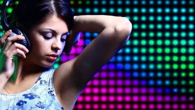 Woman enjoying music through headphones against a colorful LED backdrop