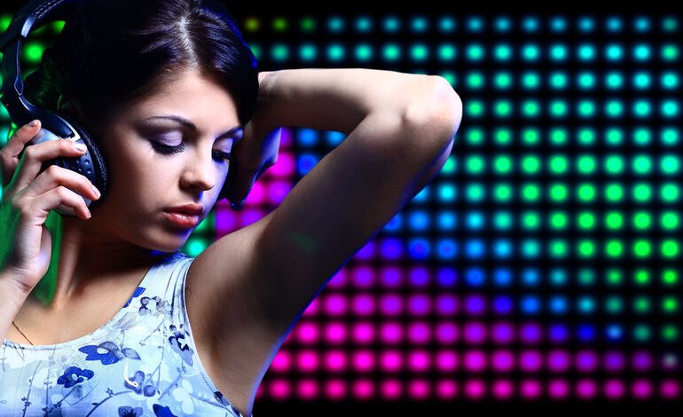 Woman enjoying music through headphones against a colorful LED backdrop