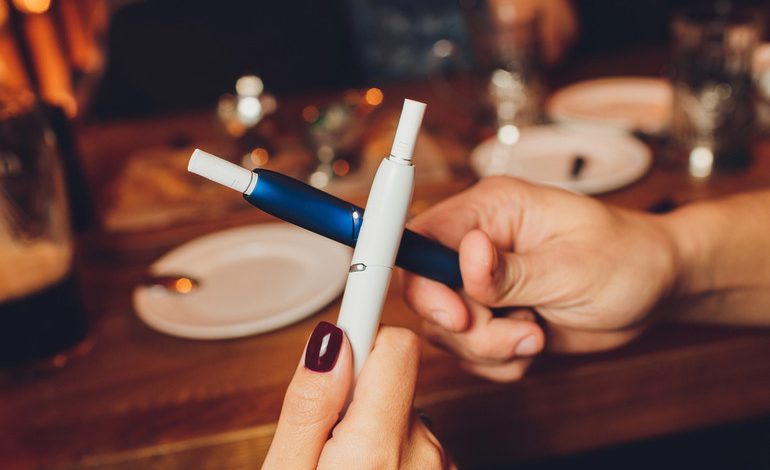 A couple holding two vape devices in a bar in San Diego