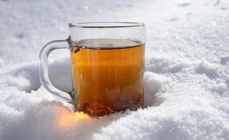 Glass of beer resting on snow at a winter festival.