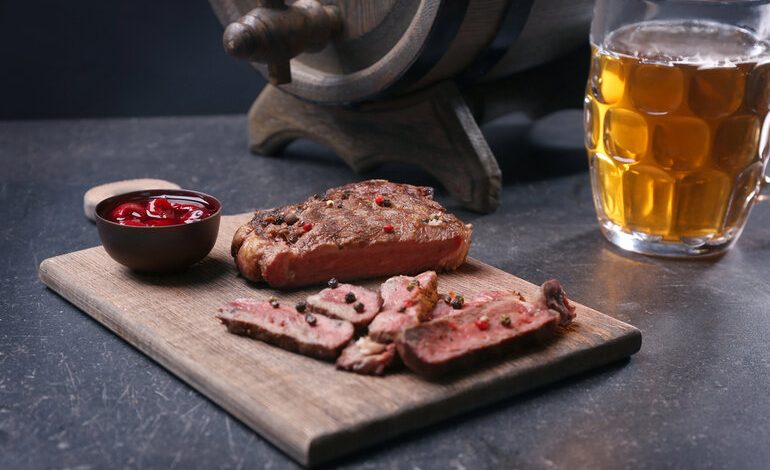 A plate of grilled meat and a glass of beer.