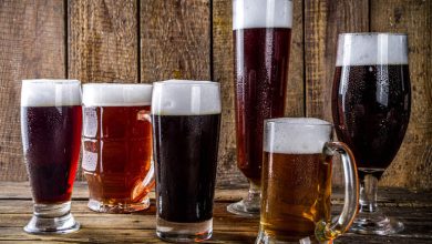 Beers for game night served in different glass styles on a rustic wooden table.