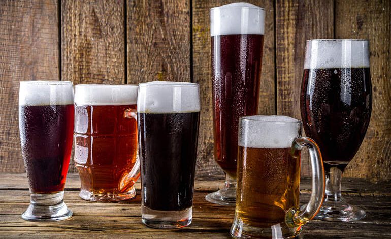 Beers for game night served in different glass styles on a rustic wooden table.