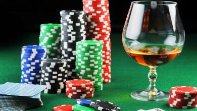 Glass of craft beer beside stacked casino chips and playing cards on a green gaming table, representing casino gaming strategies.