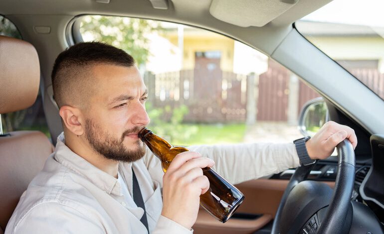 The man holding a beer bottle as he drives a car depicts a case of dangerous drunk driving in Charlotte.