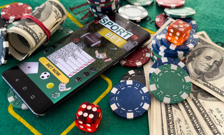 A smartphone showing an online gambling site surrounded by money and casino coins