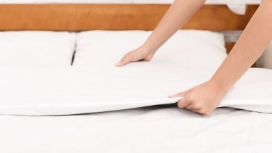 Person making a bed with fresh cooling sheets for a comfortable night’s sleep.