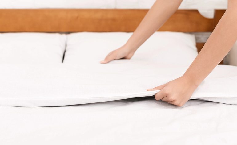 Person making a bed with fresh cooling sheets for a comfortable night’s sleep.