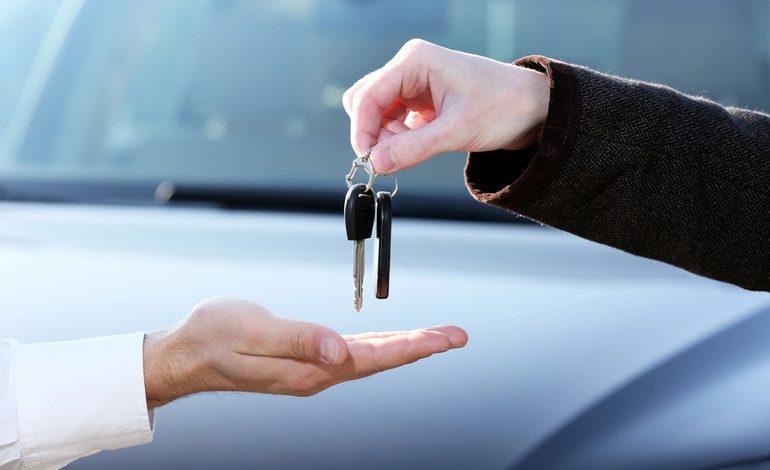 A man is receiving a car key after buying a new car.