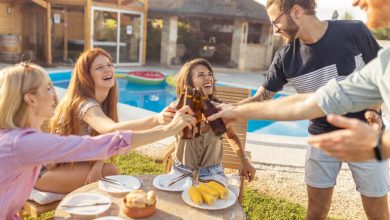 Beer drinking around a pool by the beach as friends enjoy a casual social event in San Diego as they clink their beer bottles.