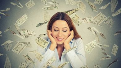 A woman is enjoying playing in a casino, and a rain of cash falls upon her.