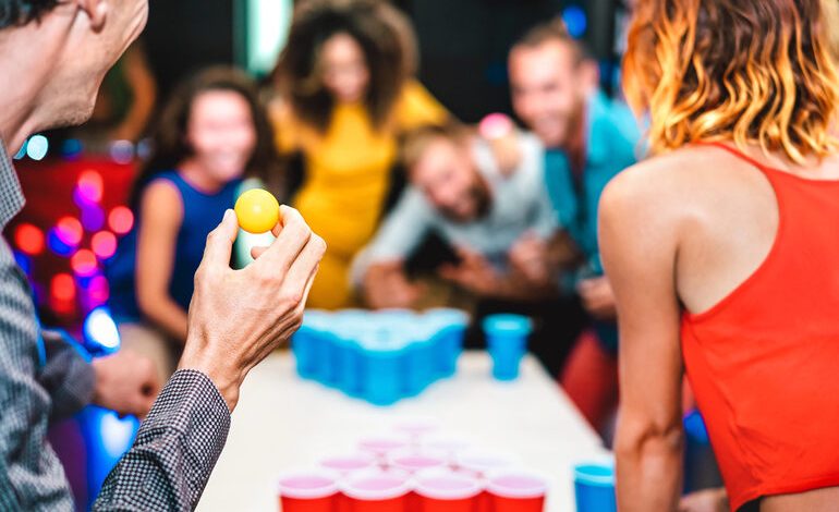 A group of friends is playing beer pong at a bar.