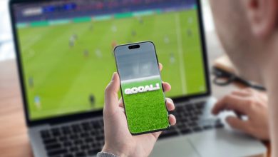 Person using a mobile sports platform while watching a live football match on a laptop, illustrating digital fan engagement in Southeast Asia.