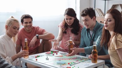 Friends playing a classic board game around a table with bottled beer.