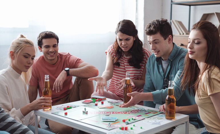Friends playing a classic board game around a table with bottled beer.