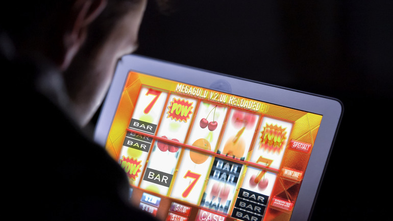 A man is playing an online slot game on his tablet.