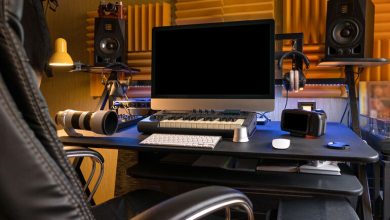 Home studio workspace with wall-mounted acoustic foam panels, studio monitors, computer, keyboard, and recording equipment.