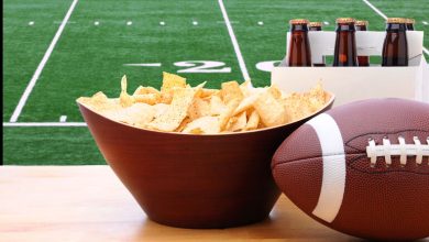 Chips, American football, and Six Pack of Beer on the table.