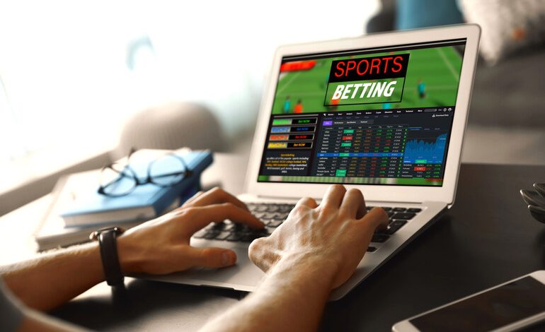 A man’s hands on a laptop, placing a sports bet.