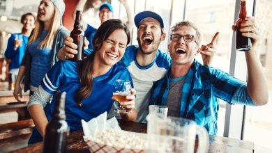 Football fans celebrating a game-day win while drinking beer at home, showing how sports sponsorships connect betting, live matches, and beer-loving audiences.