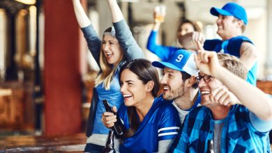 Friends cheering in a sports bar while drinking beer during a game weekend