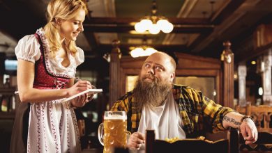 A traproom staff member taking an order from a customer with a glass of beer.