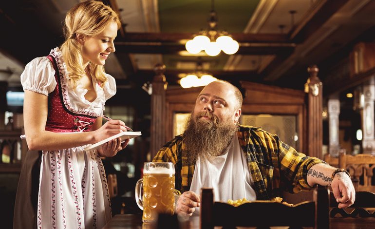 A traproom staff member taking an order from a customer with a glass of beer.