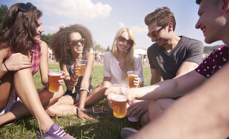 Group of friends sitting on the grass at an outdoor festival in San Diego.