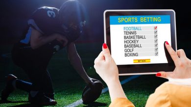 Person placing a live sports bet on a tablet during a football game, highlighting mobile betting in a social bar-like setting.