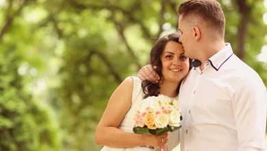 Smiling bride and groom embracing outdoors on their wedding day.