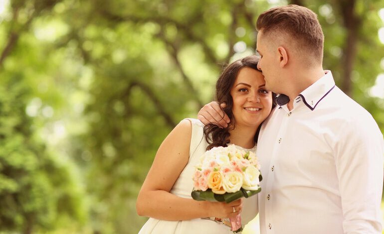 Smiling bride and groom embracing outdoors on their wedding day.