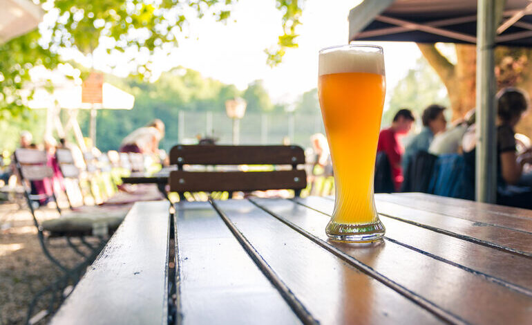 A glass of golden tank beer on a wooden table at an outdoor brewery, representing Brno’s hidden breweries and outstanding tank beer.