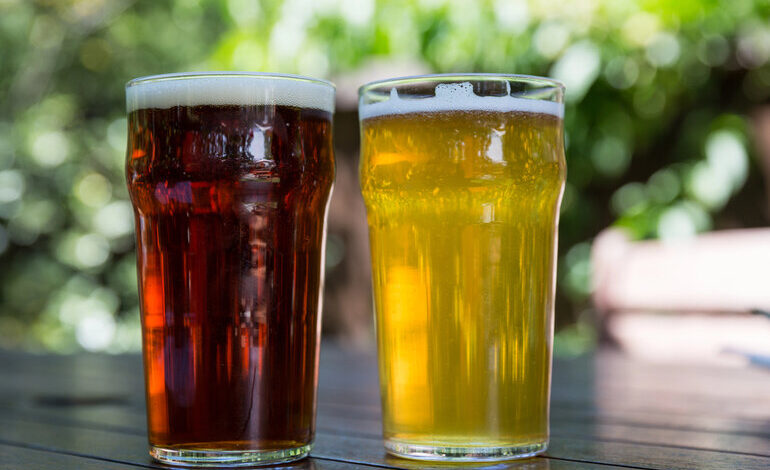 Two pint glasses on a wooden table.