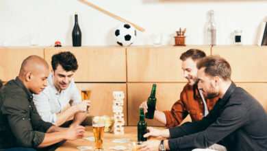 People sipping beer and playing a game together at a bar table.
