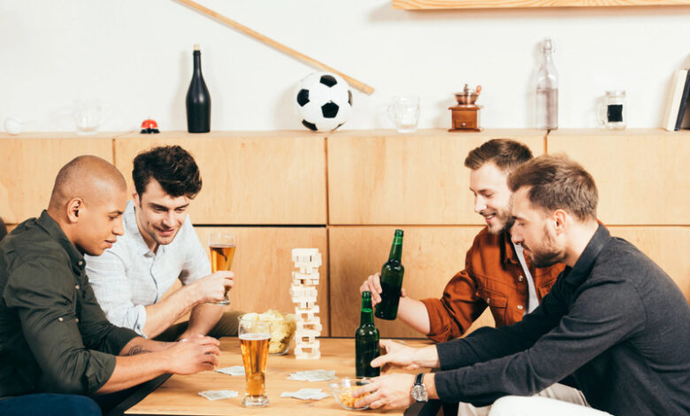 People sipping beer and playing a game together at a bar table.